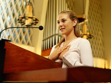 Teenage girl (16-17) in church standing at lectern, low angle