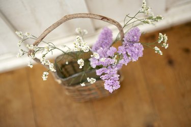 Vase of flowers in basket on wooden floor