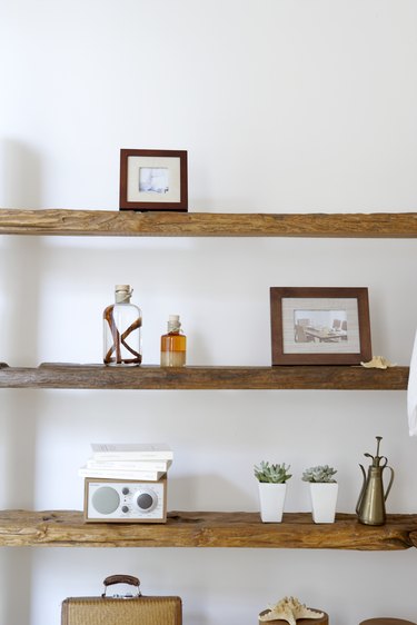 Framed photographs, decorative jars and potted plants on natural wooden shelves