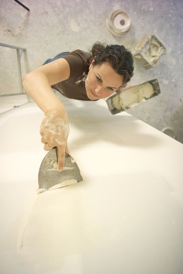 Woman applying joint compound to wall