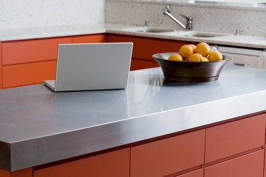 Laptop and bowl of fruit on kitchen counter