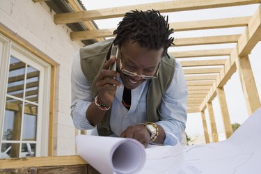 African man on cell phone looking at blueprints