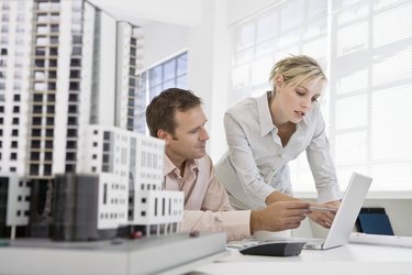 Architects working at laptop computer next to scale model