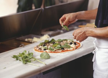 Man making pizza on table in kitchen, mid section, elevated view