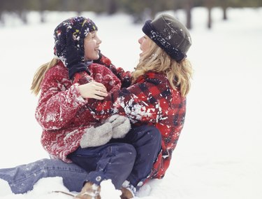 Mother and daughter (6-7) sitting in snow