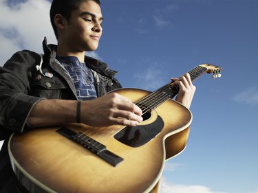 Teenage boy (15-17) playing guitar, low angle view