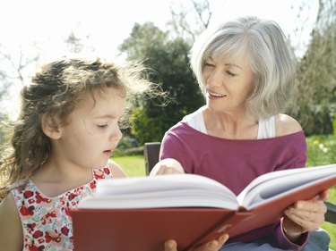 Grandmother and granddaughter (9-11) looking at photo album in garden