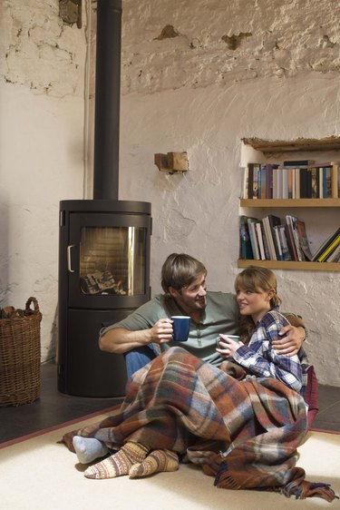 Couple snuggling by wood stove indoors