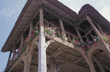Low angle view of cottage with balcony and flowers