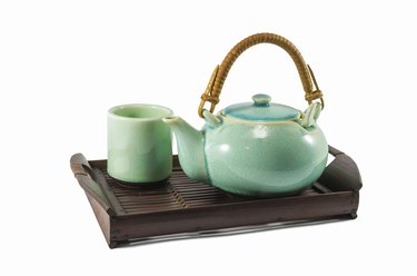 Chinese green teapot and teacups on the wooden trivet
