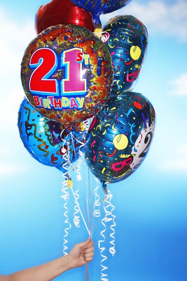 Woman holding twenty first birthday balloons