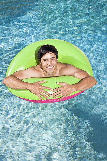 Man in swimming pool with flotation device