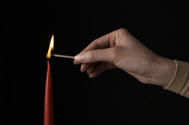 Woman lighting candle (focus on candle)