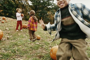 Three Children Playing in a Field With Pumpkins