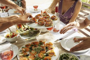 Mid Section of a Woman Passing a Plate of Canapes Around a Table of Men