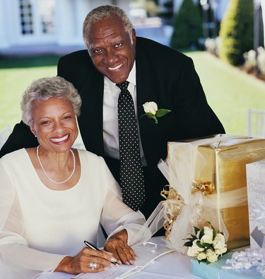 Portrait of a Mature Couple Signing a Wedding Book on a Table With Gifts