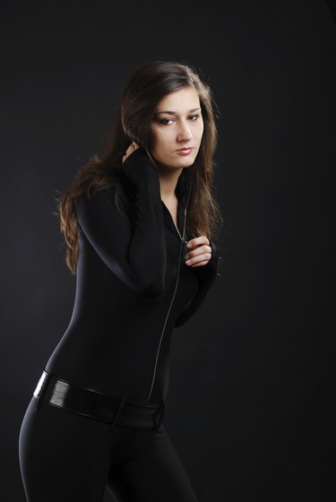 Girl in black catsuit against the dark background.