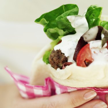 Close-up of a young woman's hand holding a pita bread sandwich