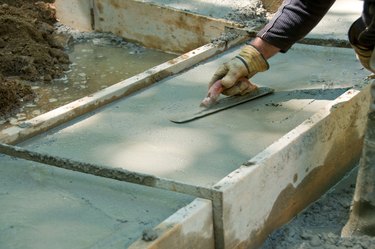 Construction worker smoothing wet concrete with trowel