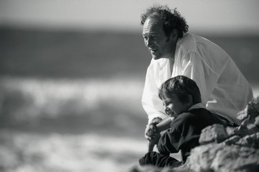 Grandfather and grandson on rocky beach