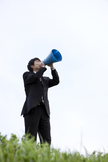 Businessman standing on grass with megaphone