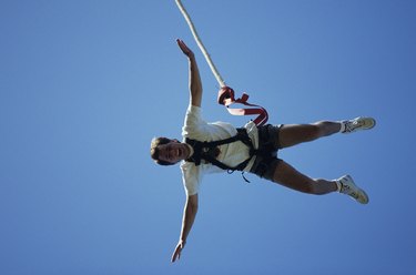 Man bungee jumping, seen against blue sky, view from below