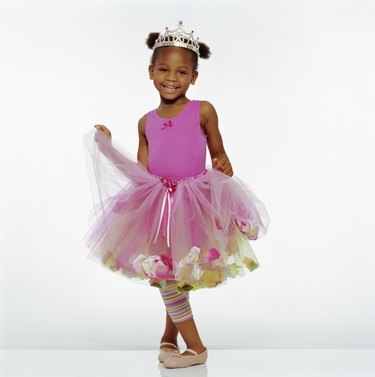 Girl (3-5) wearing tutu and crown, smiling, portrait