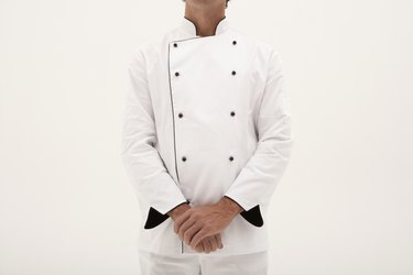 Male chef standing with hands clasped, mid section