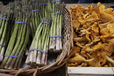 Basket of asparagus and chanterelle mushrooms on market stall