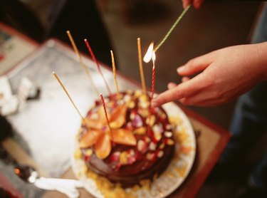 Person lighting candles on birthday cake