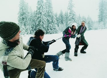 Young Couples Outdoors in the Snow Playing a Game of Tug of War