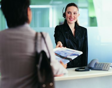 Receptionist Wearing a Headset Giving a Businesswoman a Brochure