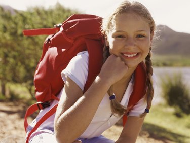 Portrait of a Girl Outdoors, Crouching Wearing a Rucksack