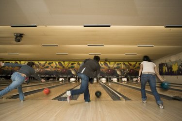 Rear view of three people bowling at a bowling alley