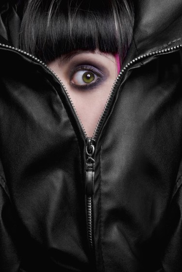 frightened green eyed girl hiding behind the zipper