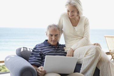 Senior Couple Sitting on an Arm Chair and Looking at a Laptop Computer