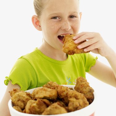 portrait of a girl (6-9) eating fried chicken