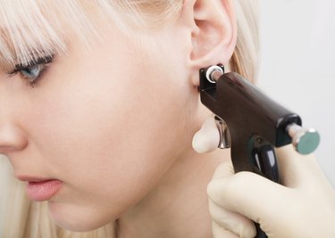Woman having ear piercing process with special equipment