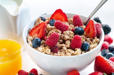 Macro close up of Healthy cereal breakfast with red fruits.Bowl of crunchy muesli and fresh orange juice.