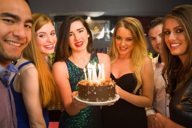 Happy friends celebrating brithday one holding birthday cake