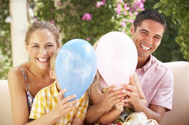 Family Sitting On Sofa Together With Balloons