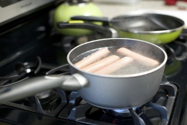 Hot dogs boil on a gas stove