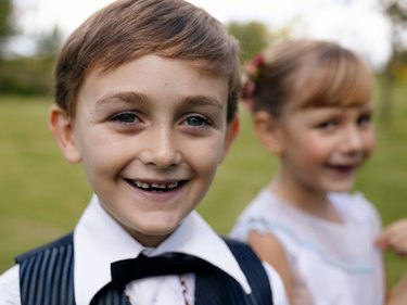 "Pageboy (6-7) with girl in background, smiling, close-up, portrait"