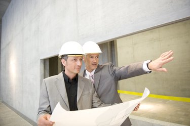 Businessmen in hard hats looking up in office building