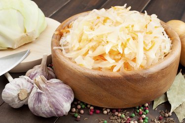 Sauerkraut with carrot in wooden bowl, garlic, spices and cabbage