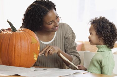 Mother carving pumpkin with her daughter