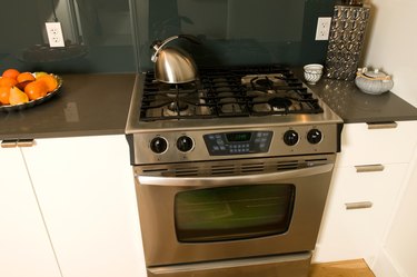 Stovetop and oven by a tray of fruit on the counter