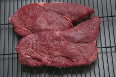 Uncooked steaks on broiler grill