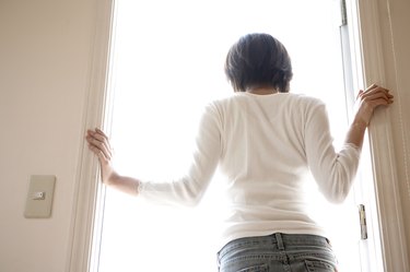 Woman standing in doorway of home, rear view