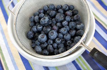 Freshly washed blueberries in vintage mesh strainer.